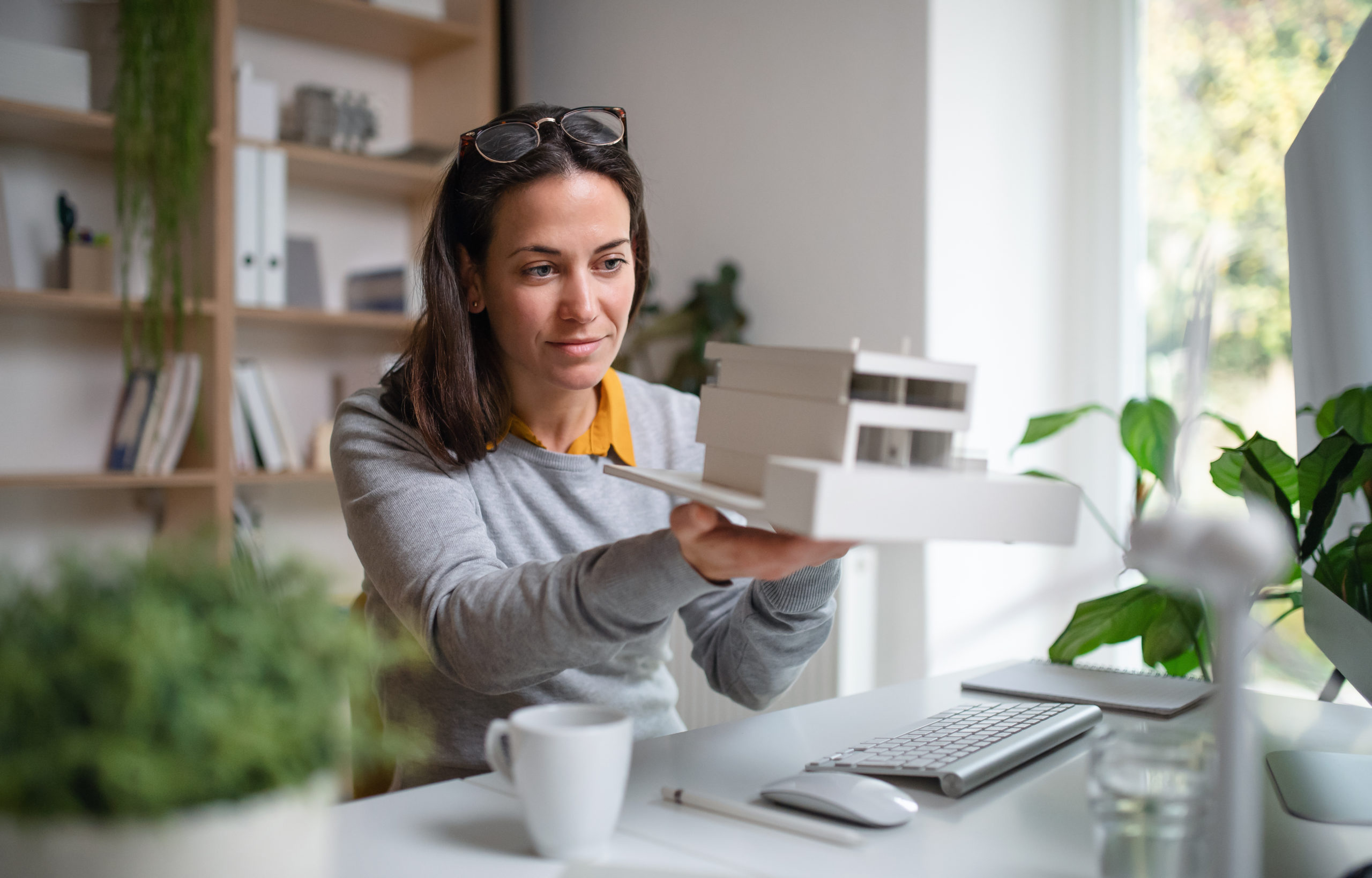 Designers Declare Article Image - Architect with model house sat at a office desk indoors